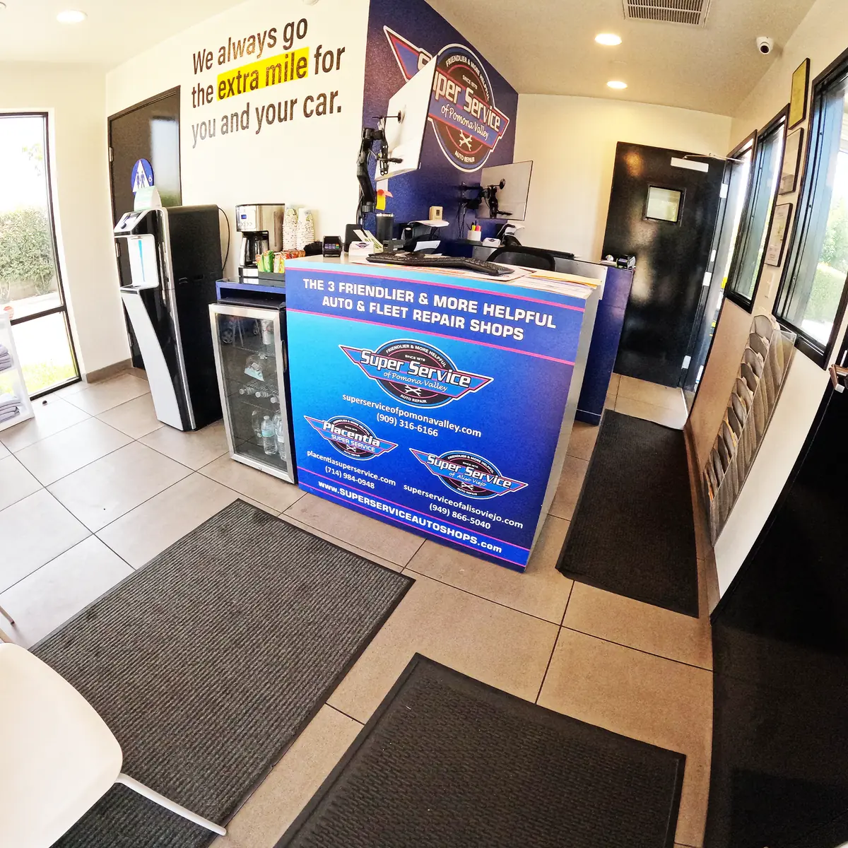 Front counter and customer lounge at Super Service of Pomona Valley, with a wall reading We always go the extra mile for you and your car
