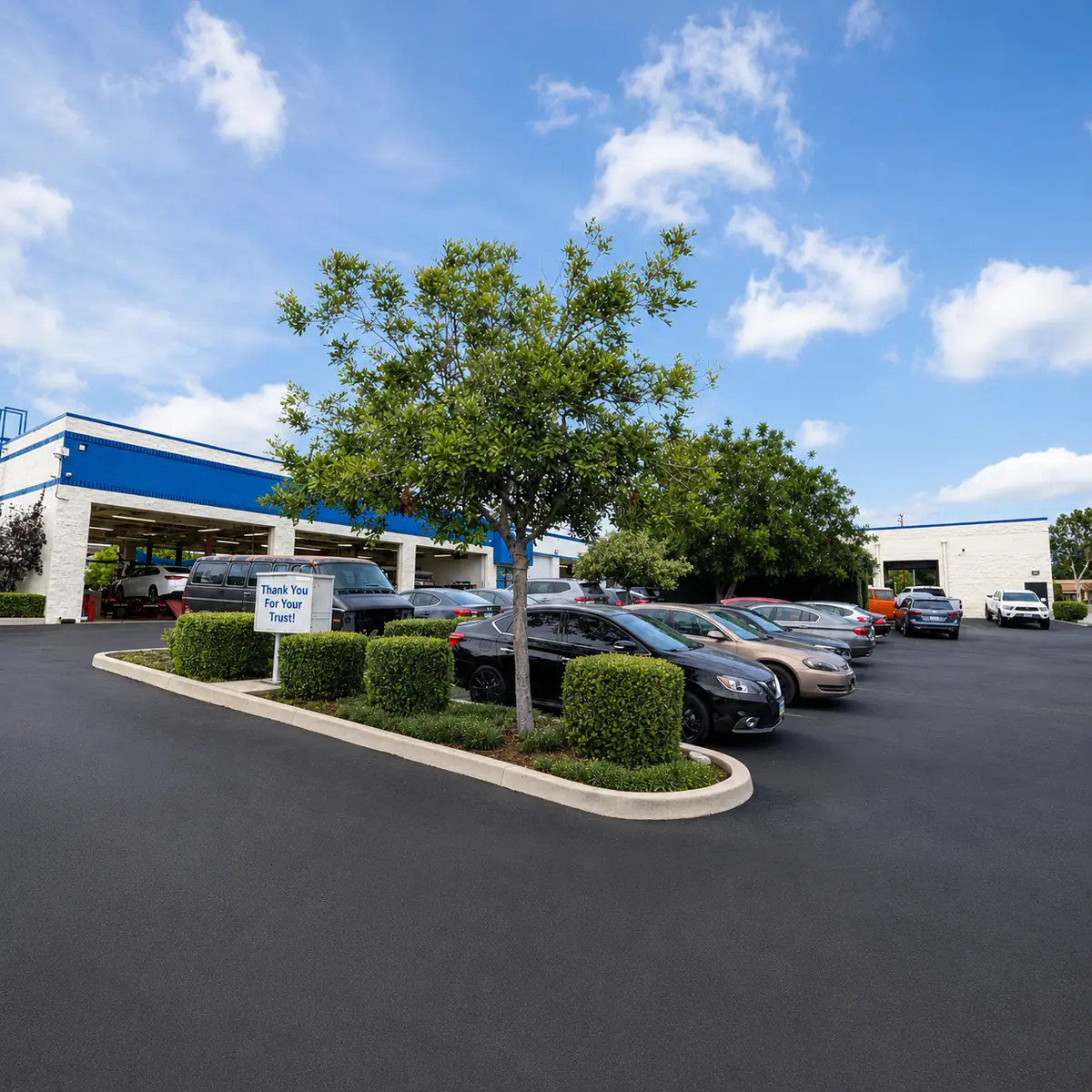 Parking lot at Super Service of Pomona Valley with a sign reading Thank You For Your Trust
